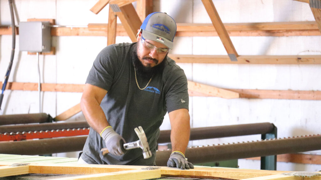 Mountain view employee hammering nails into truss