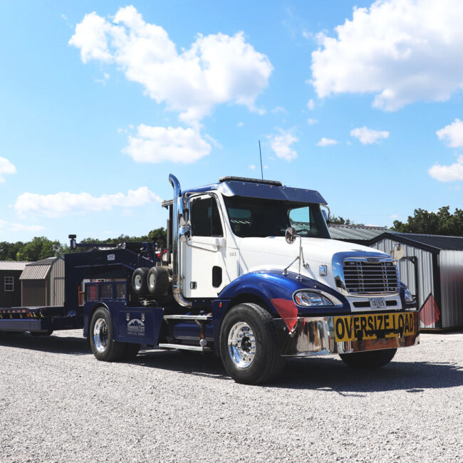 Mountain view semi in front of a row of sheds